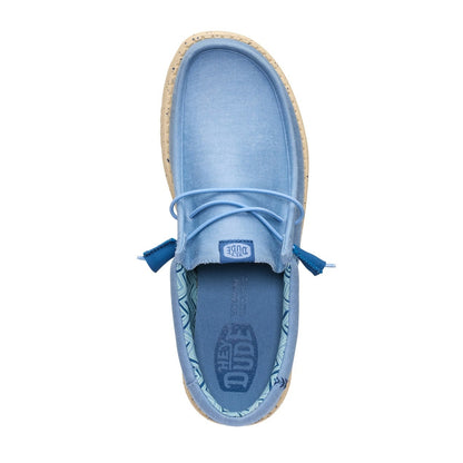 Top view of a men's Dude Wally Stretch Canvas lightweight shoe in Faded Denim Blue / Boulder Tan, with elastic laces and a Hey Dude logo printed on the removable footbed.