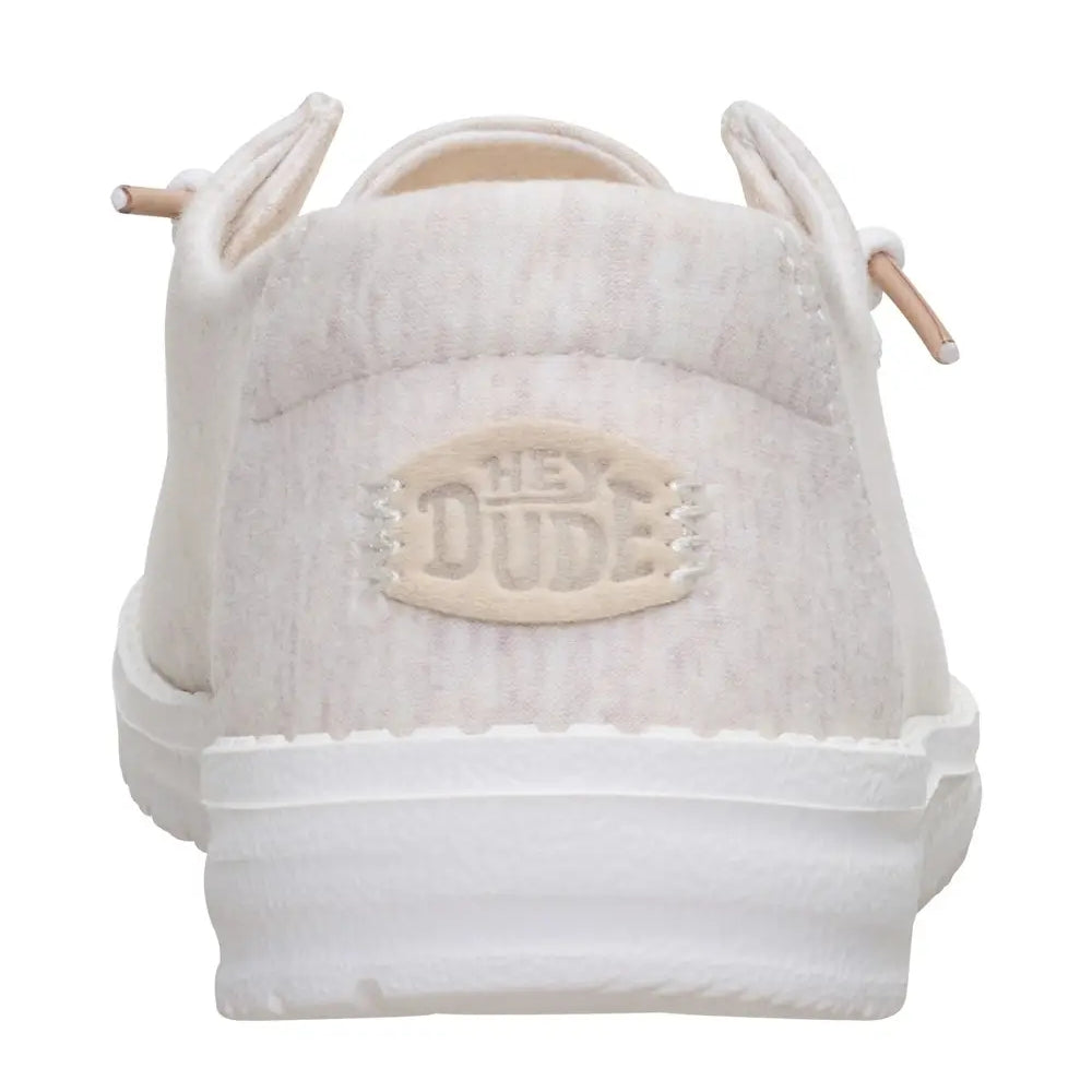 Back heel view of a women's Dude Wendy Stretch Jersey lightweight Summer shoe in Oatmeal, featuring a heathered upper fabric, white sole and Hey Dude logo on the heel.