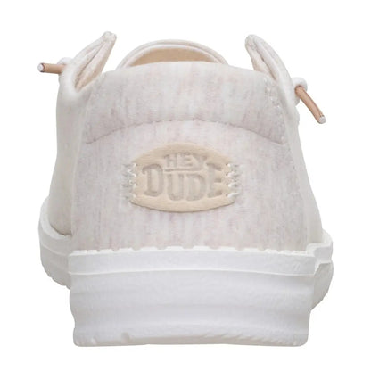 Back heel view of a women's Dude Wendy Stretch Jersey lightweight Summer shoe in Oatmeal, featuring a heathered upper fabric, white sole and Hey Dude logo on the heel.