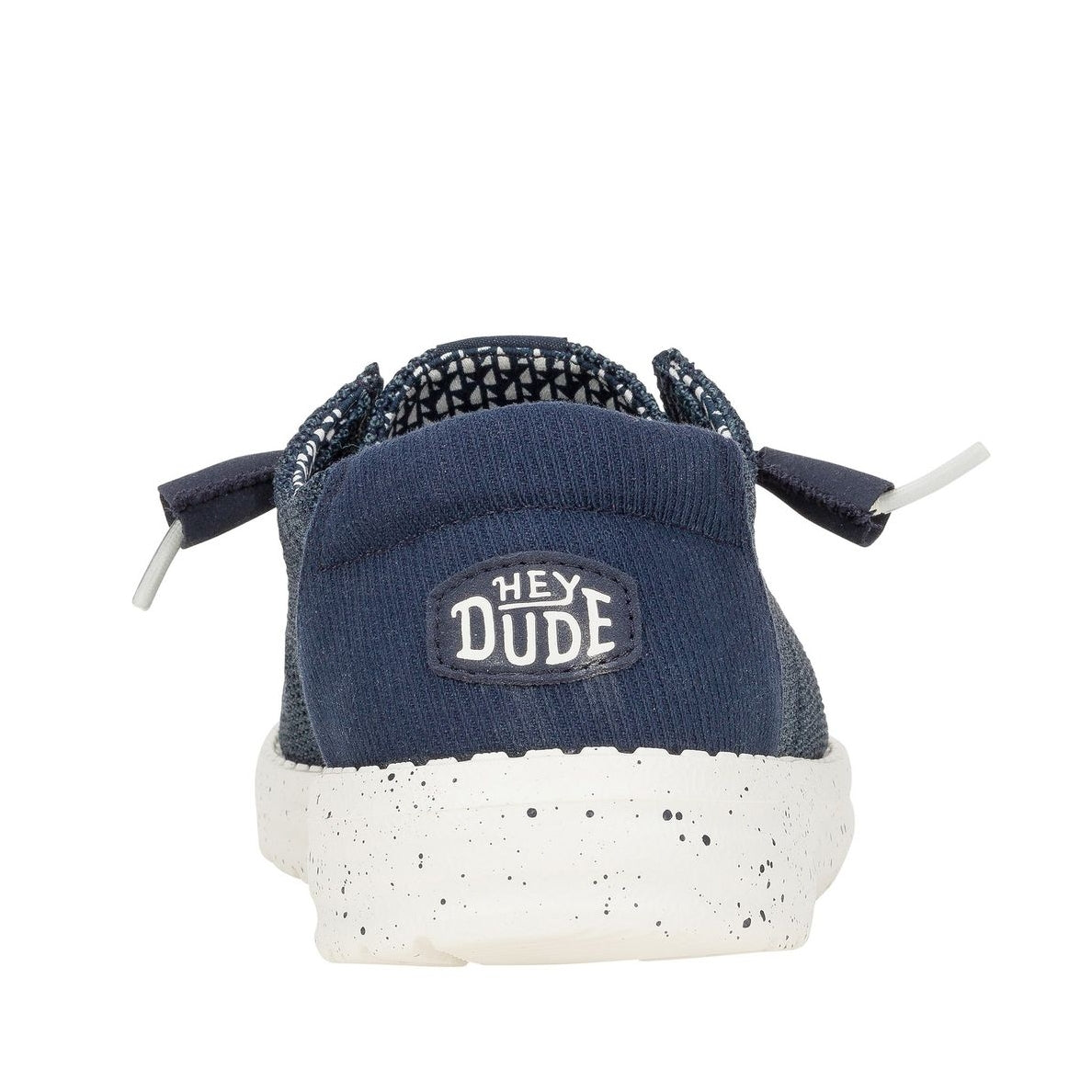 Back heel view of a women's Dude Wendy Stretch Sox shoe in Navy, featuring a Hey Dude logo on the heel.