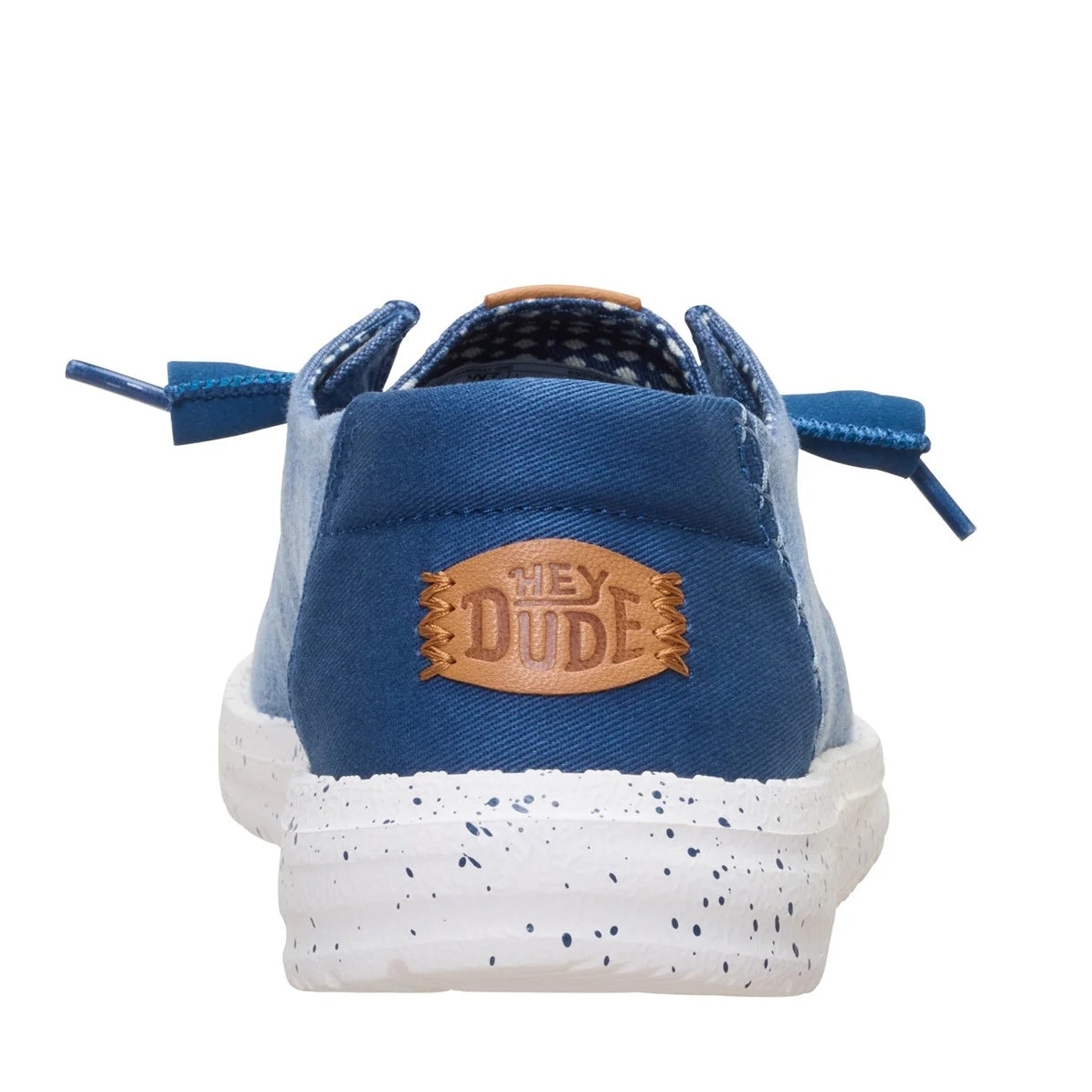 Back heel view of a women's Dude Wendy Chambray Grid shoe in Ensign Blue, featuring a speckled white sole and Hey Dude logo on the heel.