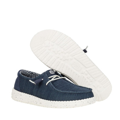 A pair of women's Dude Wendy Stretch Sox shoe in Navy, showing the bottom white outsole of one shoe.