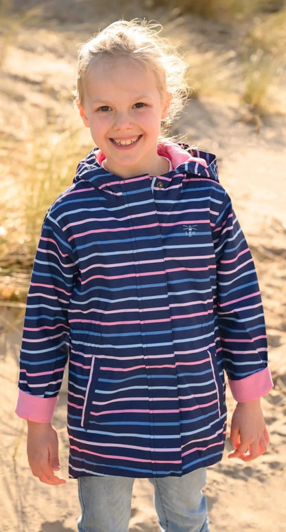 Child wearing a Lighthouse Charlotte waterproof jacket in navy with a pink and blue stripe pattern outdoors.