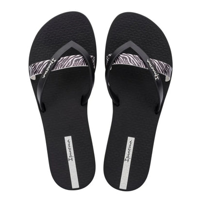 Top view of a pair of women's Ipanema Kirei flip flops, a three strap toepost design in black with a contrasting zebra print strap and textured footbed.