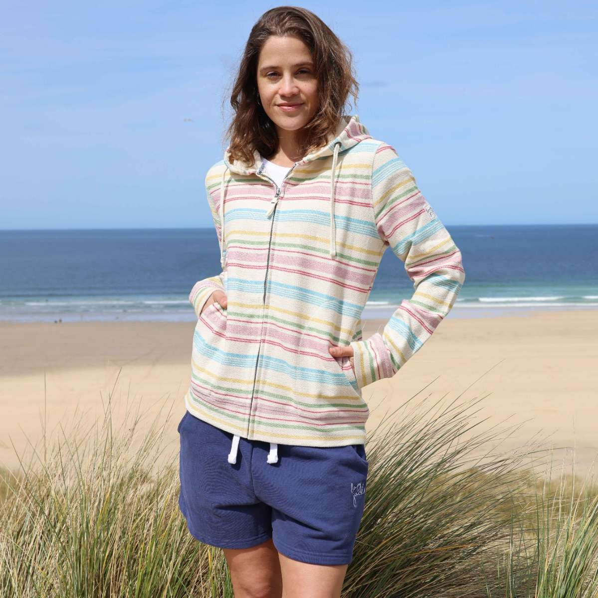 Front view of a woman wearing a Lazy Jacks LJ302 full zip hoodie in multicoloured pastel stripes with tummy pockets