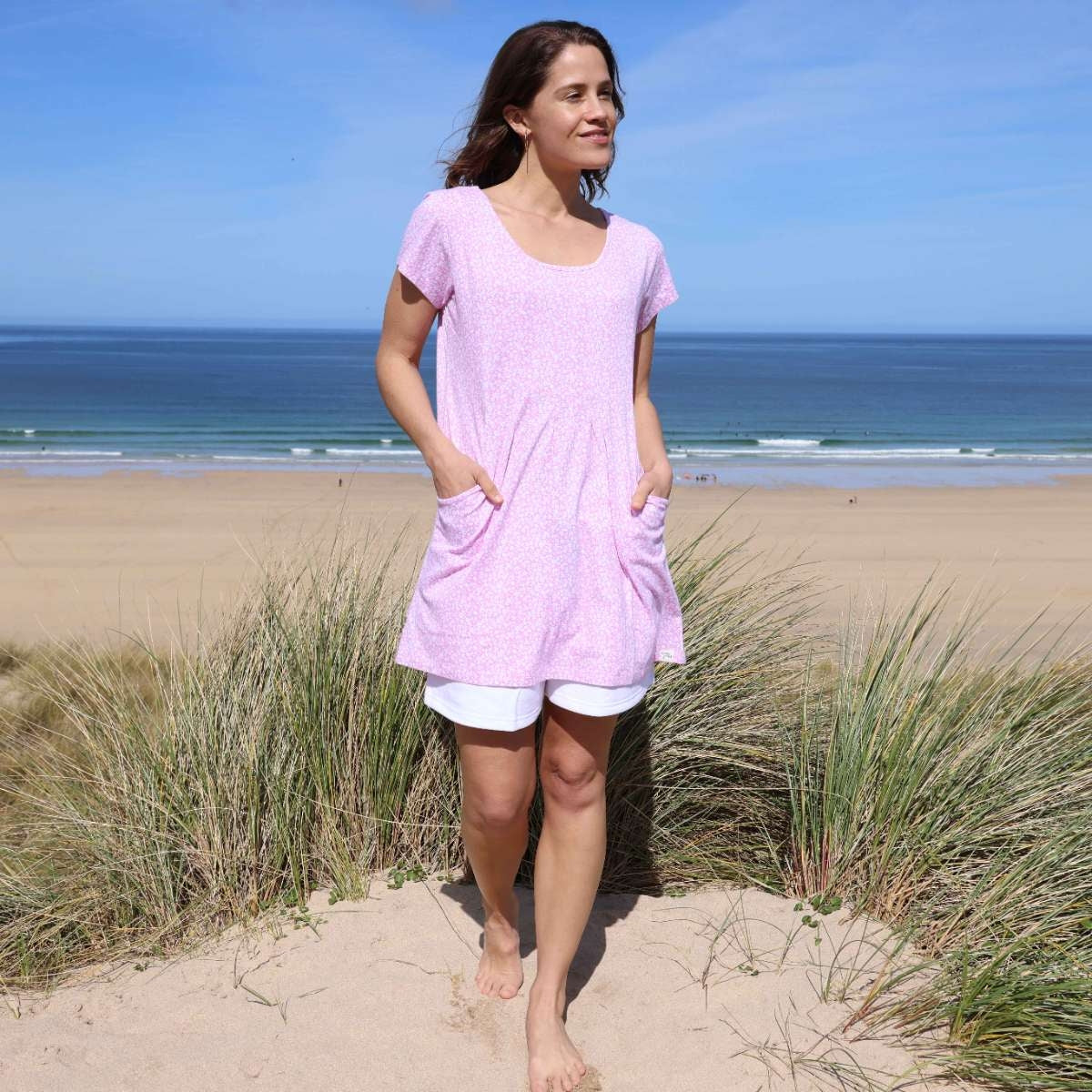 Woman wearing a Lazy Jacks short sleeve LJ116 tunic in pink with a white ditsy floral pattern with white shorts