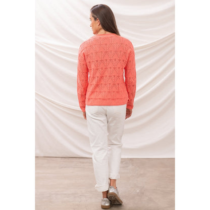 Back view of a woman wearing a Lighthouse Eden jumper in a bright Sugar Coral colour with pointelle style knit.