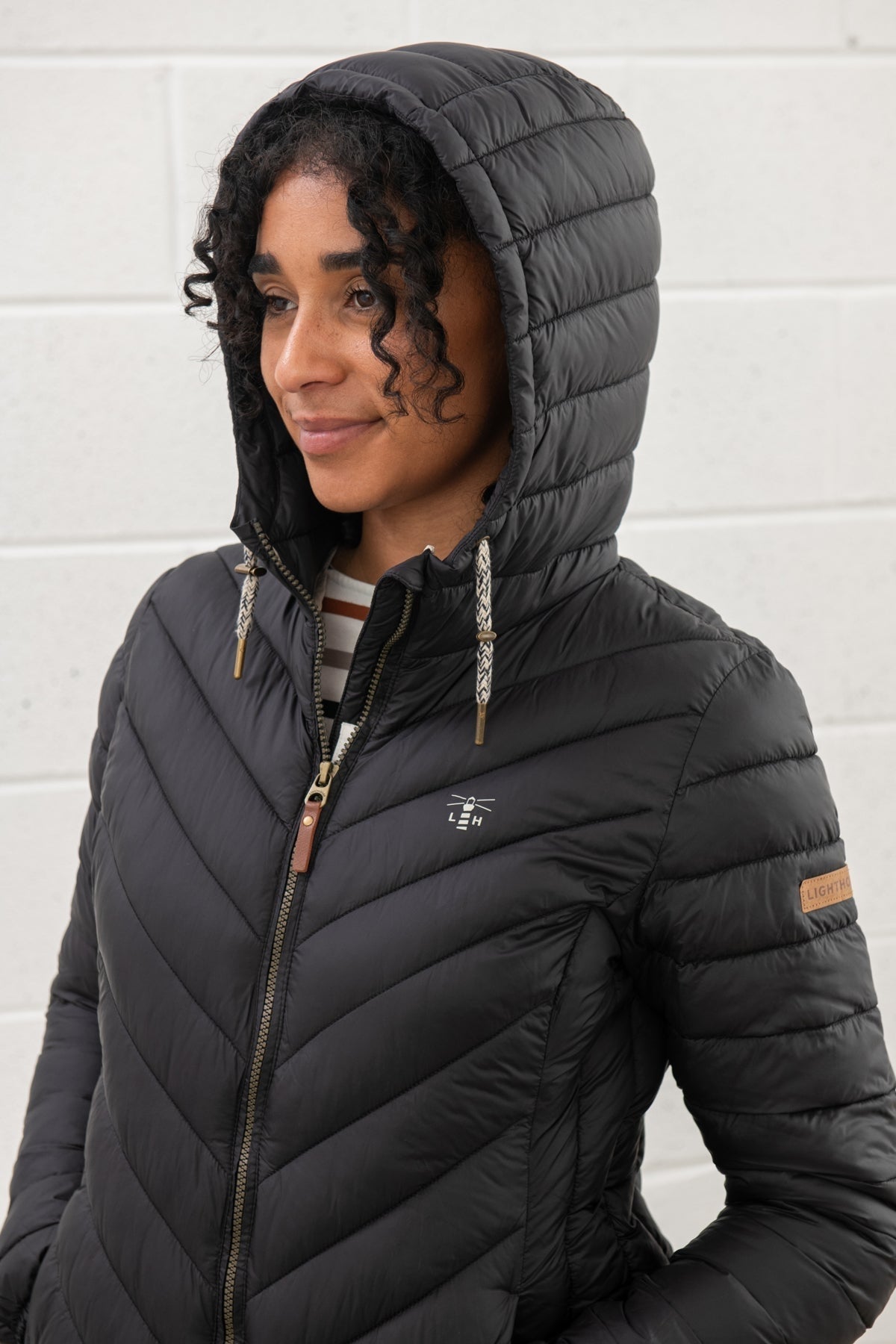 Lighthouse black padded coat womens with hood and zipper front worn by woman with curly hair