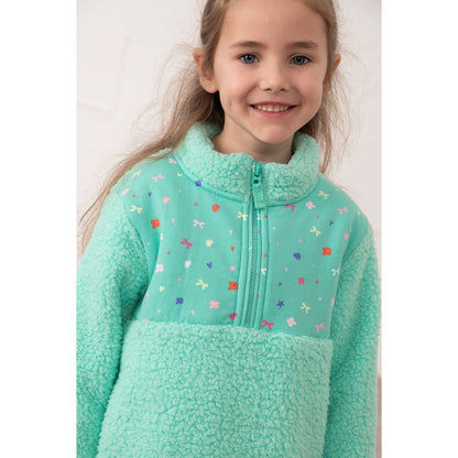 Close-up view of a girl wearing a Lighthouse Cassie fleece, in mint green with a tiffany bows, hearts, stars and floral print on the chest.