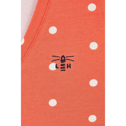 Close-up view of a Lighthouse short sleeve Ariana v-neck t-shirt in coral with a white dot pattern and a small Lighthouse logo.