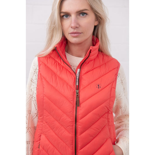 Close-up view of a woman wearing a Lighthouse padded Laurel Gilet in Sugar Coral over a cream jumper.