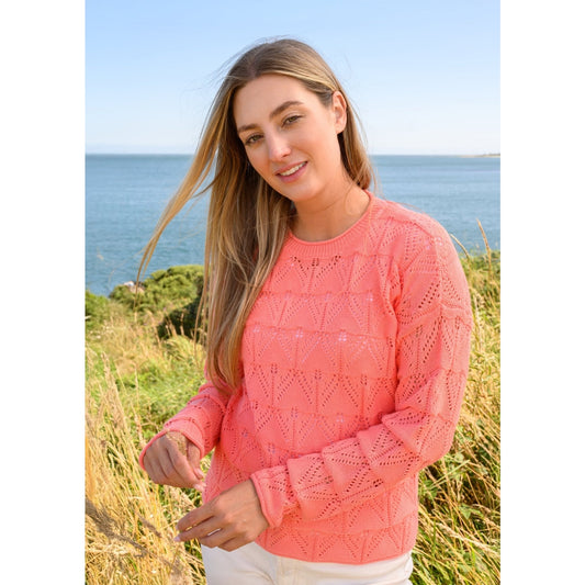 Front view of a woman wearing a Lighthouse Eden jumper in a bright Sugar Coral colour with pointelle style knit.