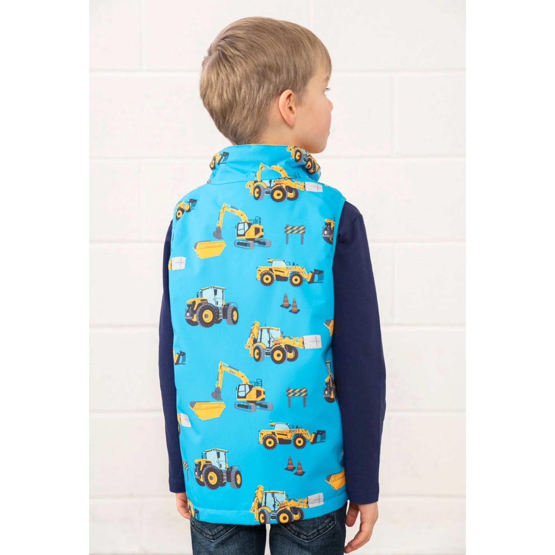 Lighthouse kids blue gilet JCB print worn by child showing back with construction vehicle designs