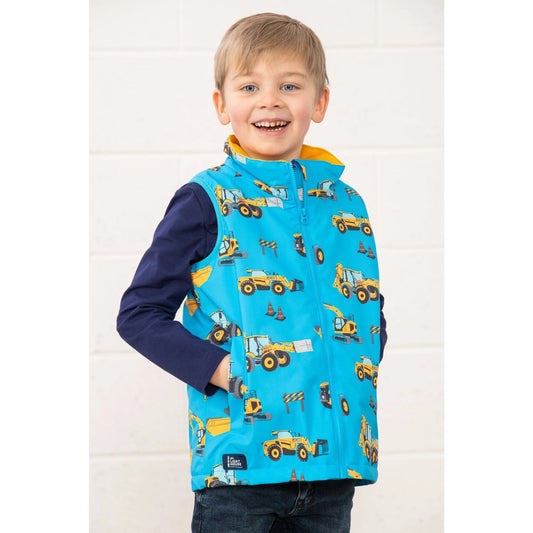 Front view of a Lighthouse kids blue gilet JCB print worn by smiling child with hands in pockets