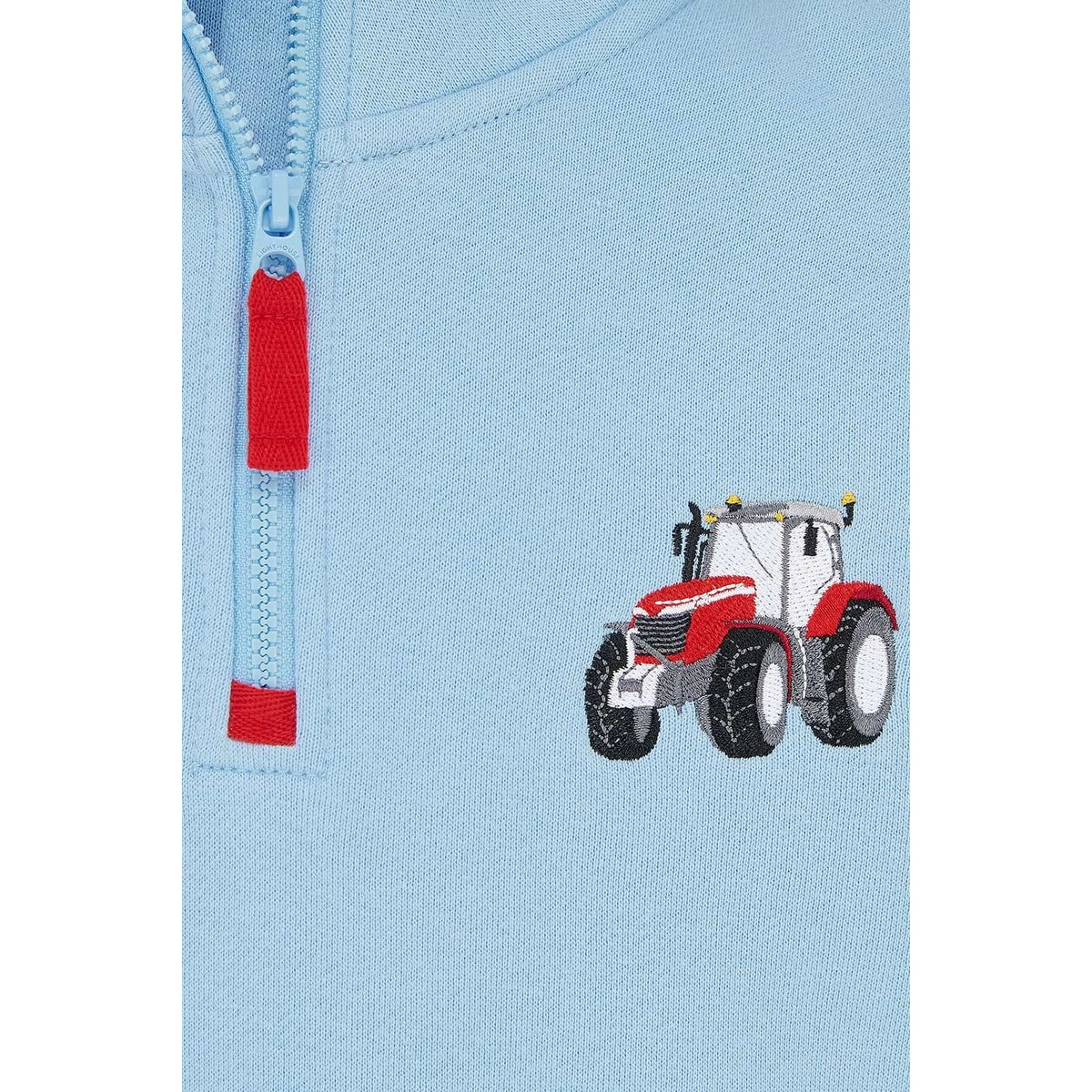 Close-up view of a Lighthouse kids Jonah 1/4 zip sweatshirt in sky blue with red trim and a red embroidered tractor applique on the chest.
