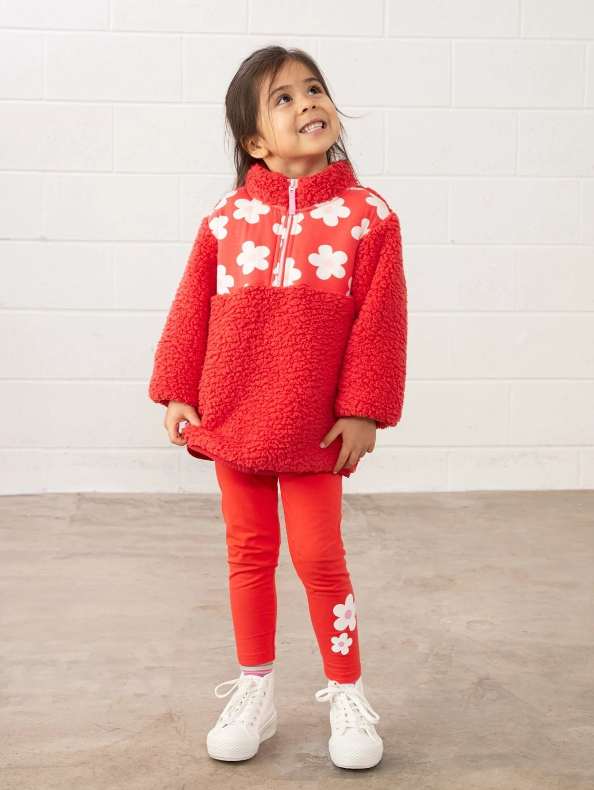 Girl wearing Lighthouse kids coral leggings with white flower print and white sneakers
