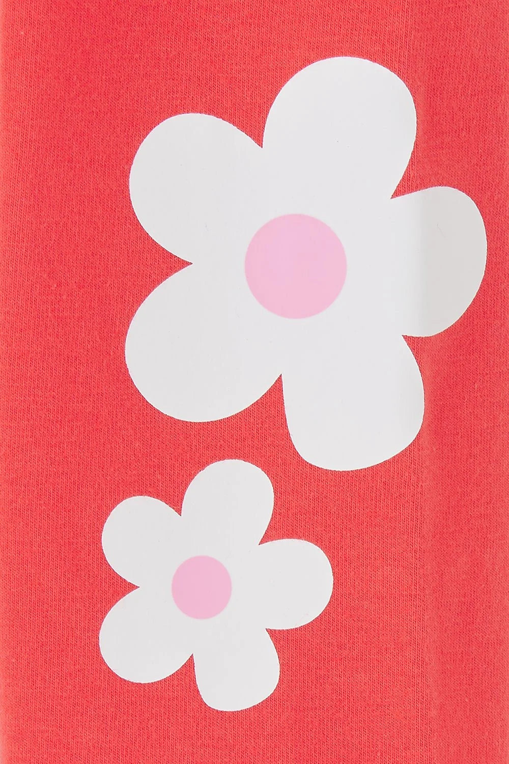 Close-up of Lighthouse kids coral leggings featuring white and pink flower prints on coral fabric