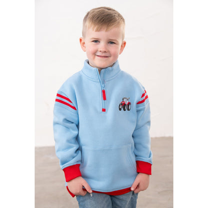 Front view of a boy wearing a Lighthouse Jonah 1/4 zip sweatshirt in sky blue with red trim and a red embroidered tractor applique on the chest.