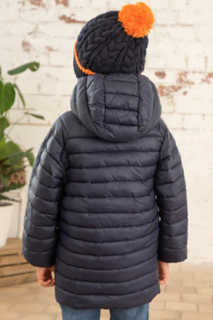 Back view of a child wearing a Lighthouse kids navy Carter padded coat with a hood and blue knit hat with orange pompom