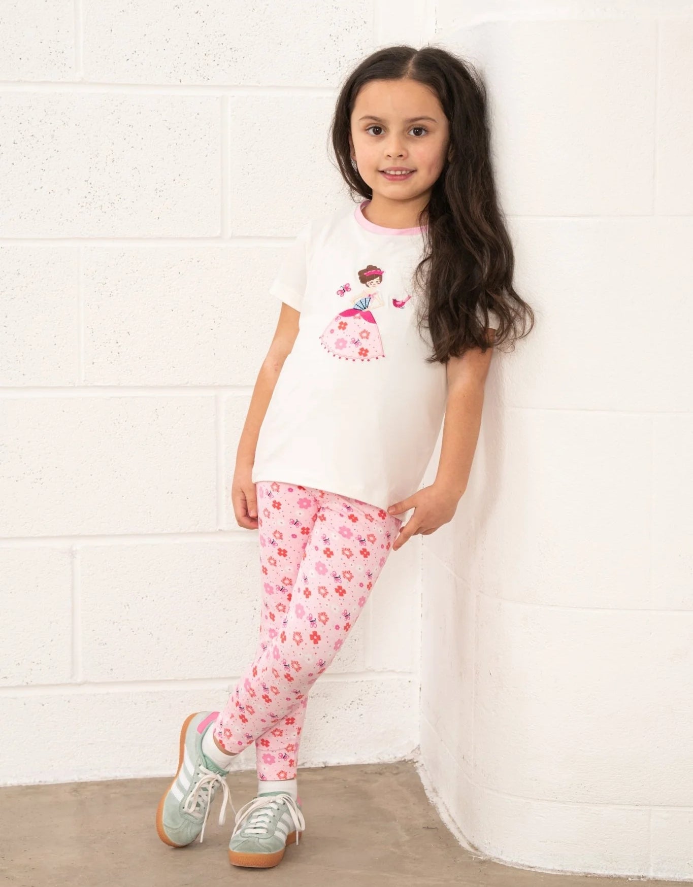 Lighthouse kids Princess Tee worn by girl with long hair paired with pink floral leggings and sneakers