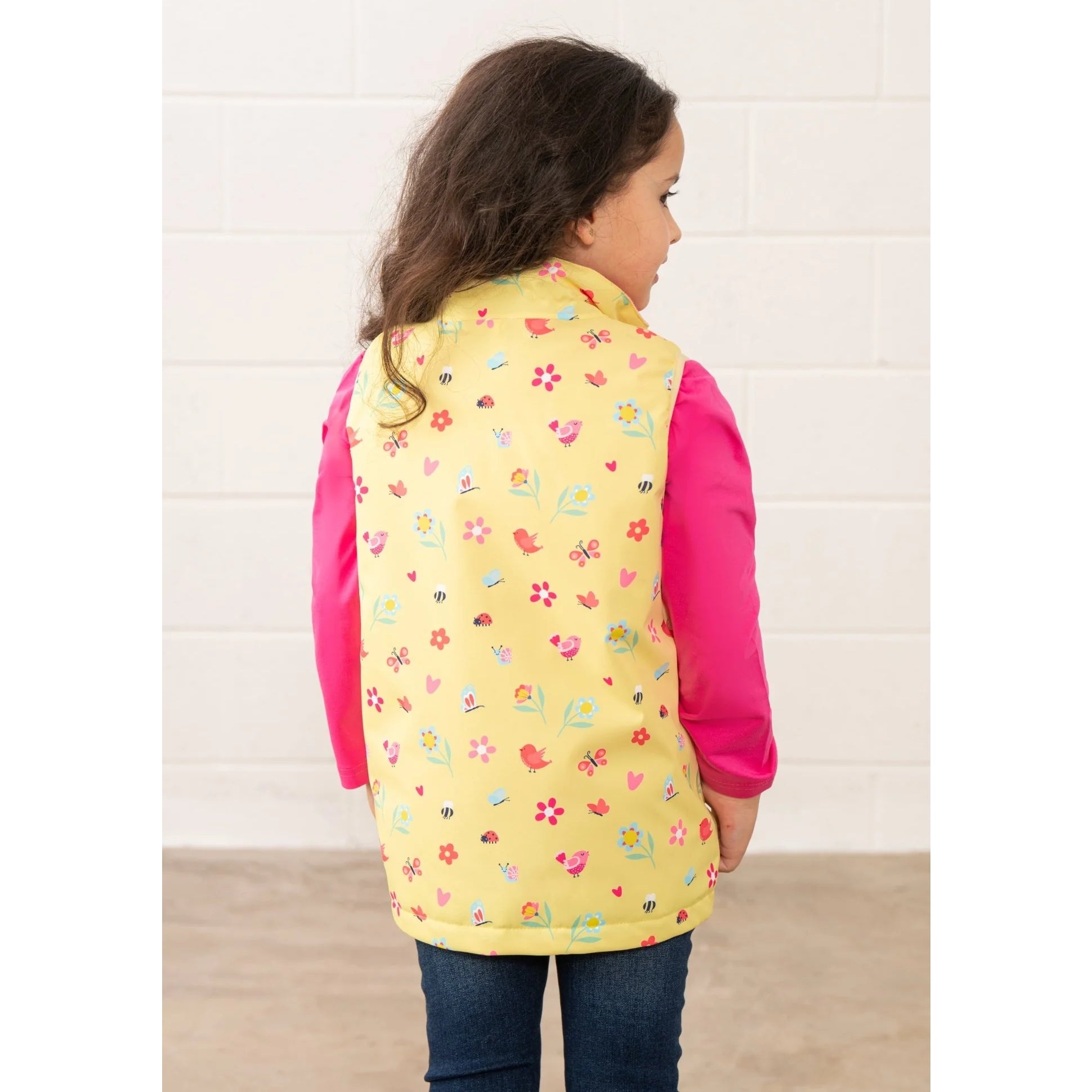 Lighthouse kids yellow floral gilet worn by child showing back with colorful flower and bug pattern