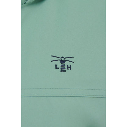 Close-up view of the green fabric with embroidered lighthouse logo of a Lighthouse waterproof Beachcomber II waterproof jacket in Basil green.
