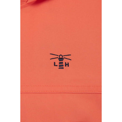 Close-up view of the embroidered logo and fabric of a womens Beachcomber II waterproof jacket in Coral.