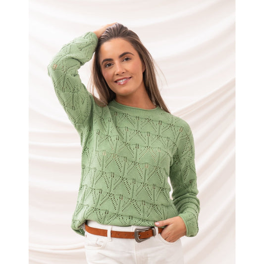 Main front view of a woman wearing a Lighthouse Eden knitted jumper in Soft Sage Green with a geometric pointelle knit pattern.