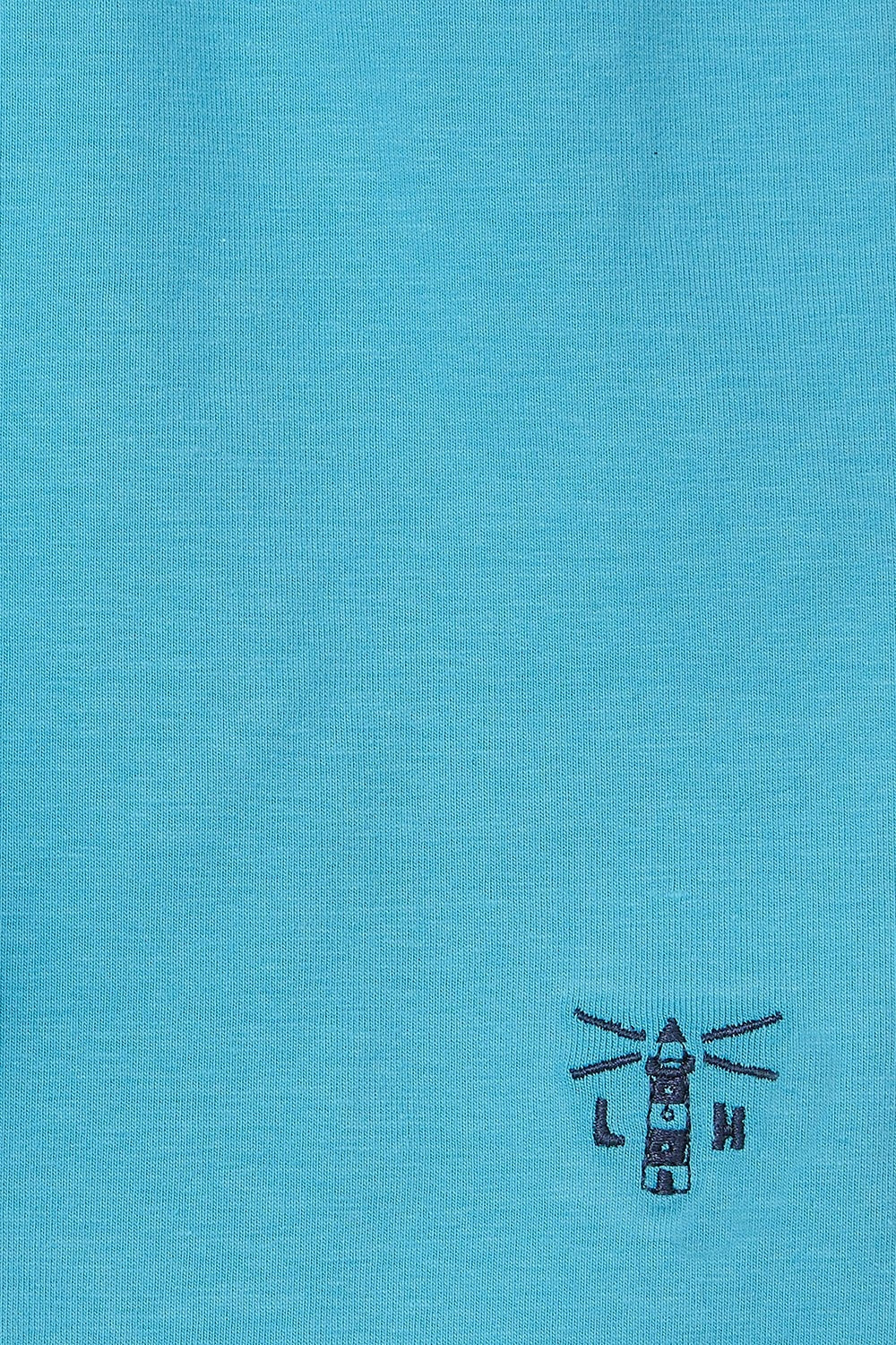 Close-up of turquoise fabric with Lighthouse Polly Shorts Turquoise logo embroidery