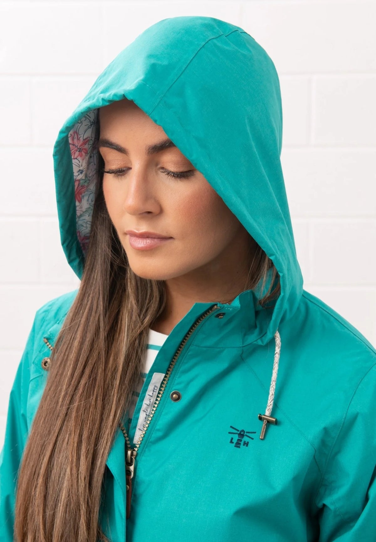 Lighthouse teal womens waterproof jacket with hood and drawstring detail worn by woman