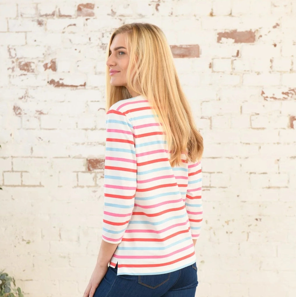 Back view of a woman wearing a Lighthouse Ariana top in Watermelon Pink stripe with a brick wall background
