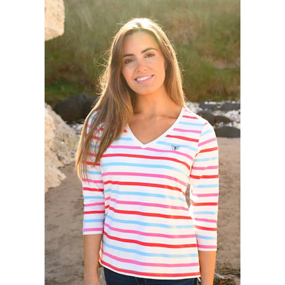 Woman wearing a Lighthouse v-neck Ariana 3/4 sleeve top in Watermelon Pink Stripe, standing outdoors with natural light