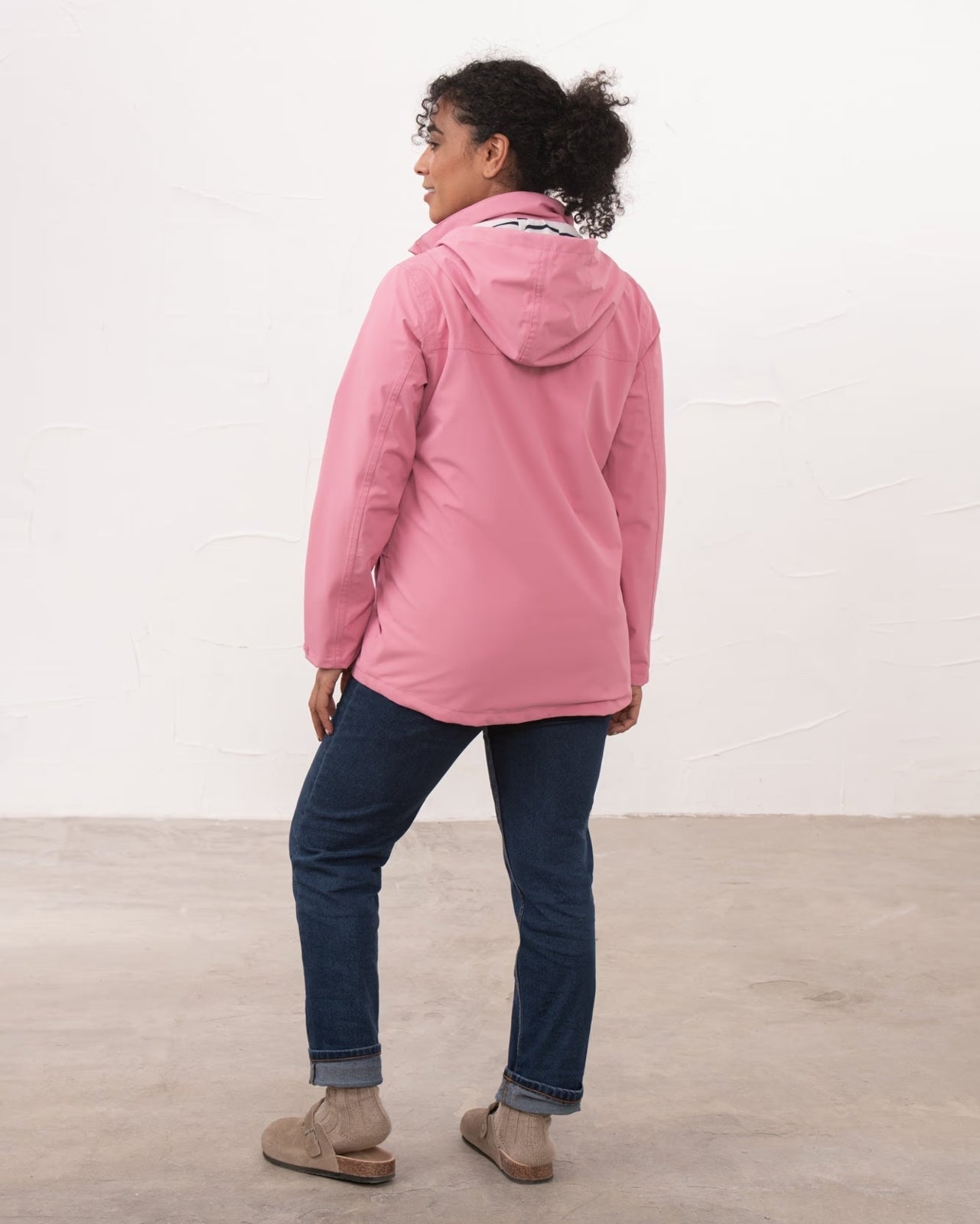 Back view of a womens Beachcomber II waterproof jacket in Pink with blue jeans.