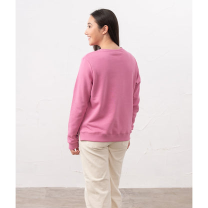 Back view of a woman wearing a Lighthouse Seaside crew neck sweatshirt in Pink with cream trousers.