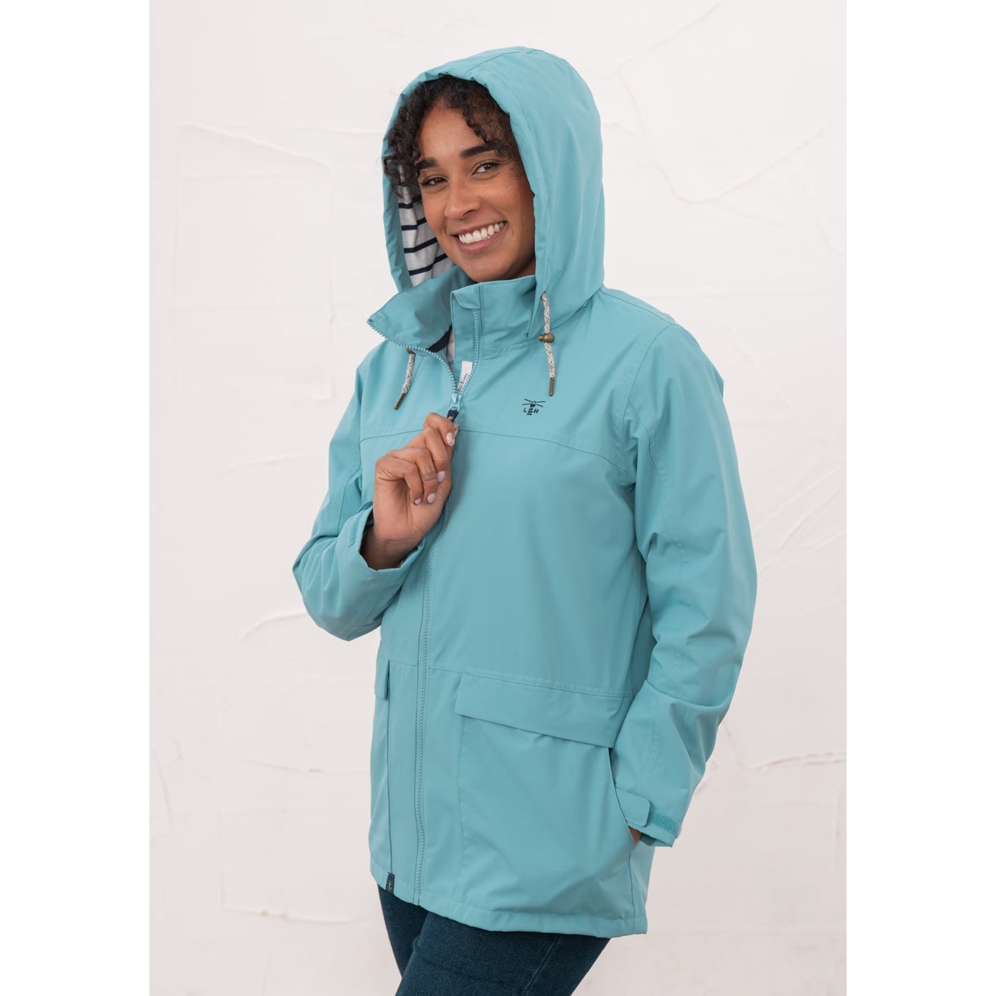 Woman wearing a Beachcomber II waterproof jacket in Blue with the hood up.
