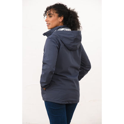 Back view of a woman wearing a Lighthouse navy Beachcomber II waterproof jacket.