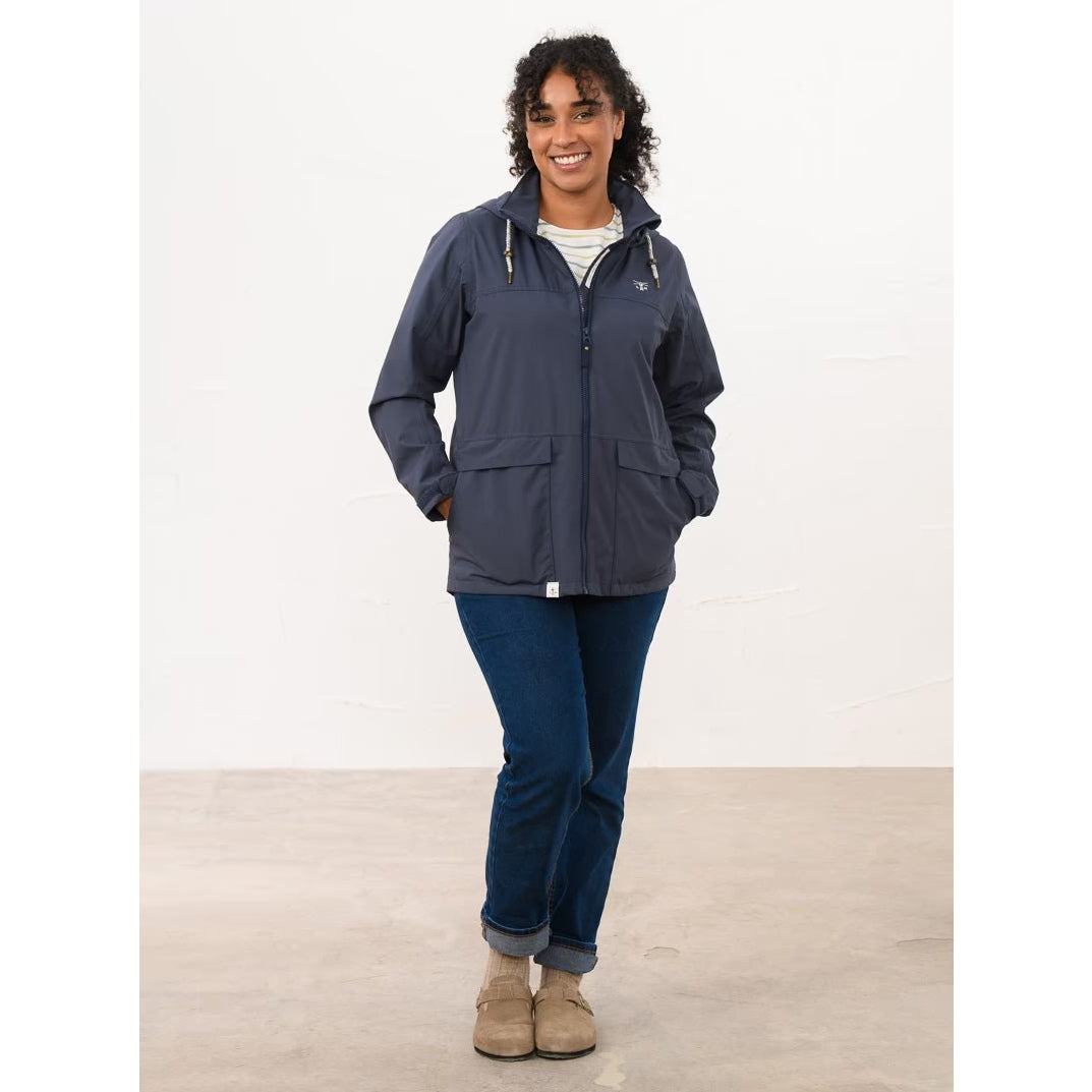 Woman wearing a Lighthouse navy Beachcomber II waterproof jacket with blue jeans.