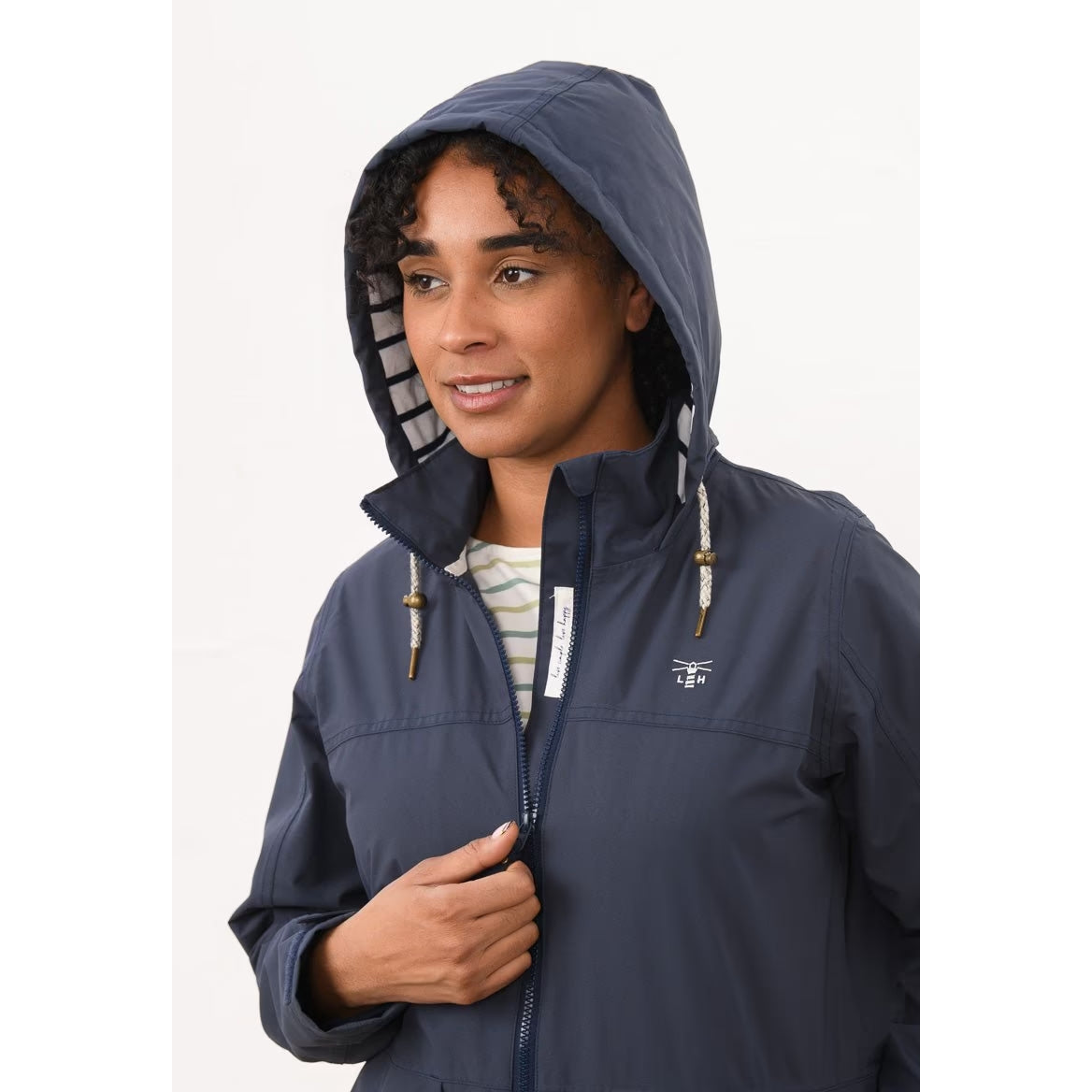 Close-up view of a woman wearing a Lighthouse navy Beachcomber II waterproof jacket with the hood up.