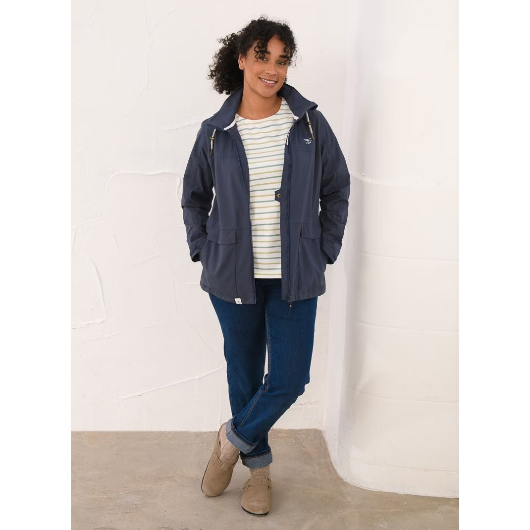 Woman wearing a Lighthouse navy Beachcomber II waterproof jacket unzipped with blue jeans.