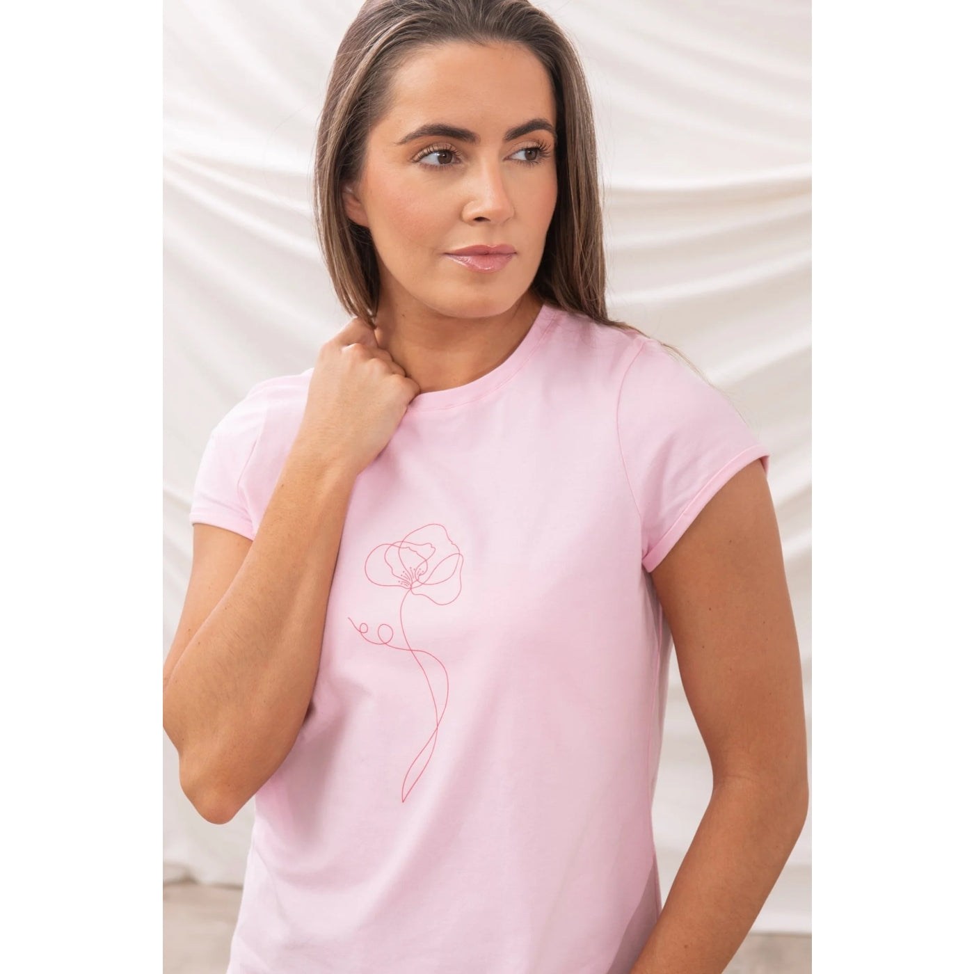 Woman wearing a pink Lighthouse Causeway t-shirt with a flower print against a white background