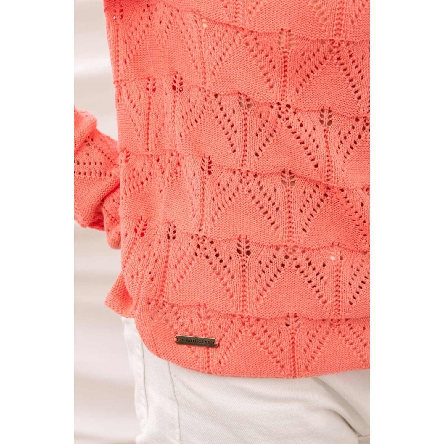 Close-up view of the pointelle knit fabric of a Lighthouse Eden jumper in a bright Sugar Coral colour.