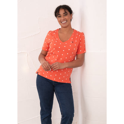 Front view of a woman wearing a Lighthouse short sleeve Ariana v-neck t-shirt in coral with a white dot pattern.