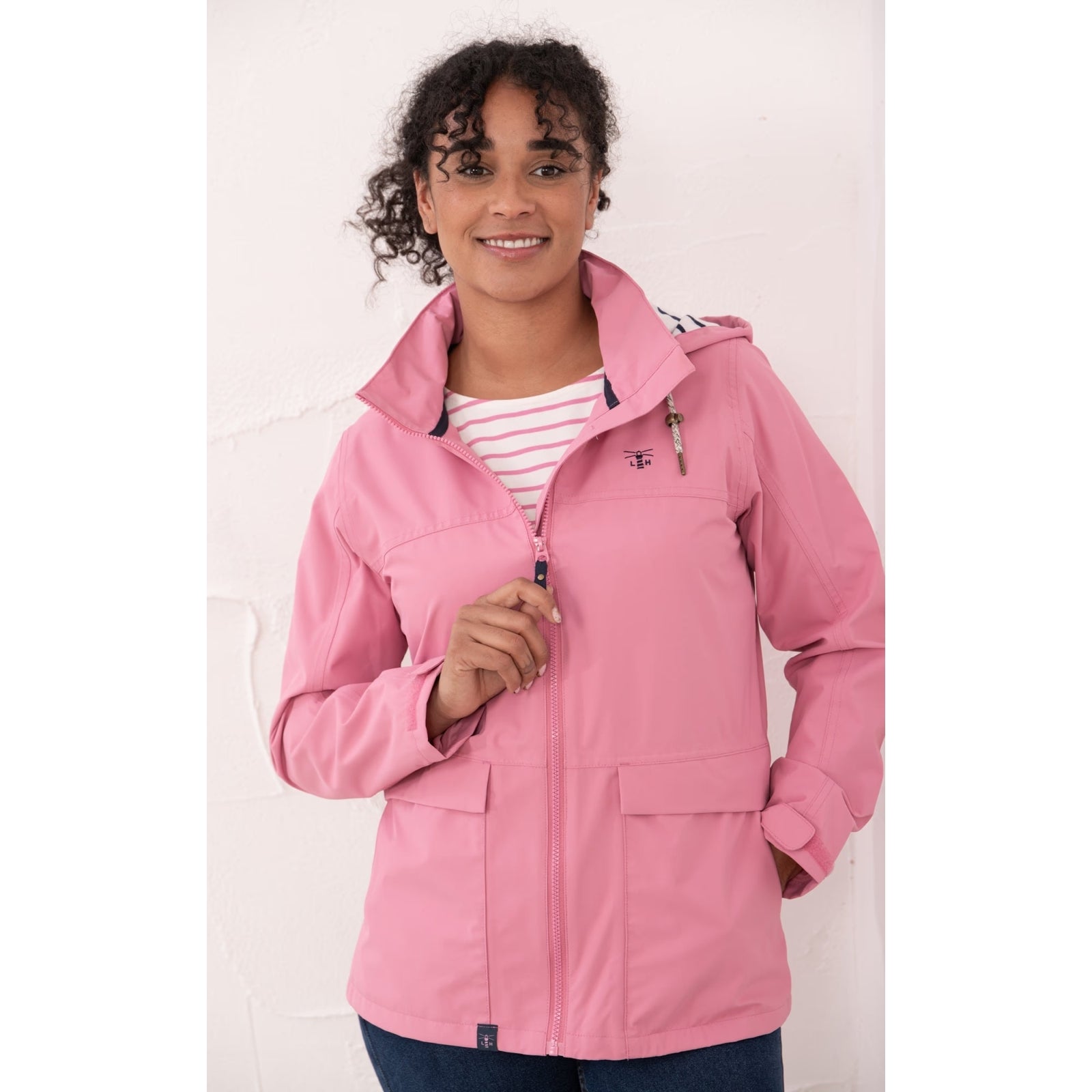 Front view of a woman wearing a Beachcomber II waterproof jacket in Pink with a stripy hood lining.