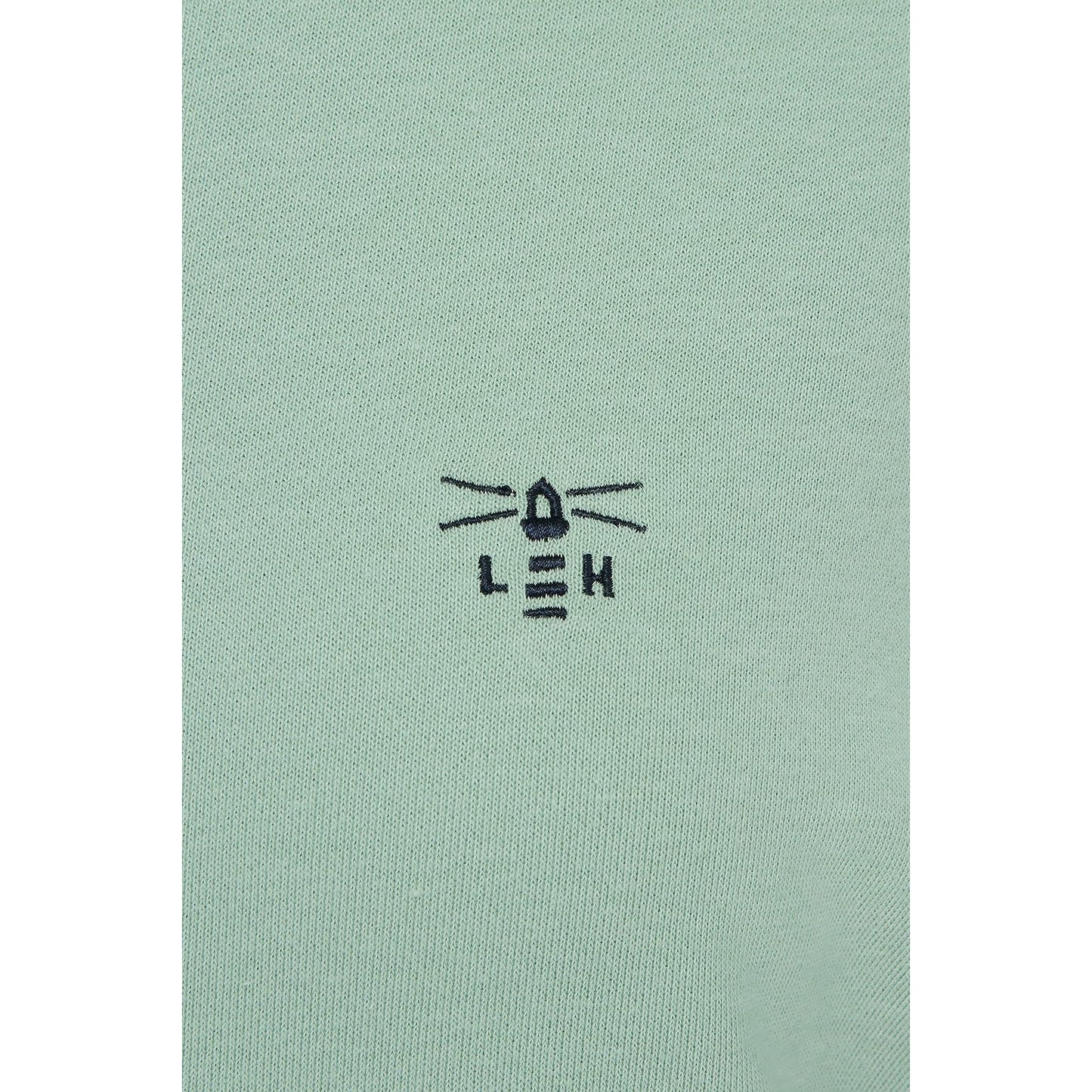 Close-up view of the embroidered logo of a Lighthouse women's Seaside crew neck sweatshirt in Pastel Green.