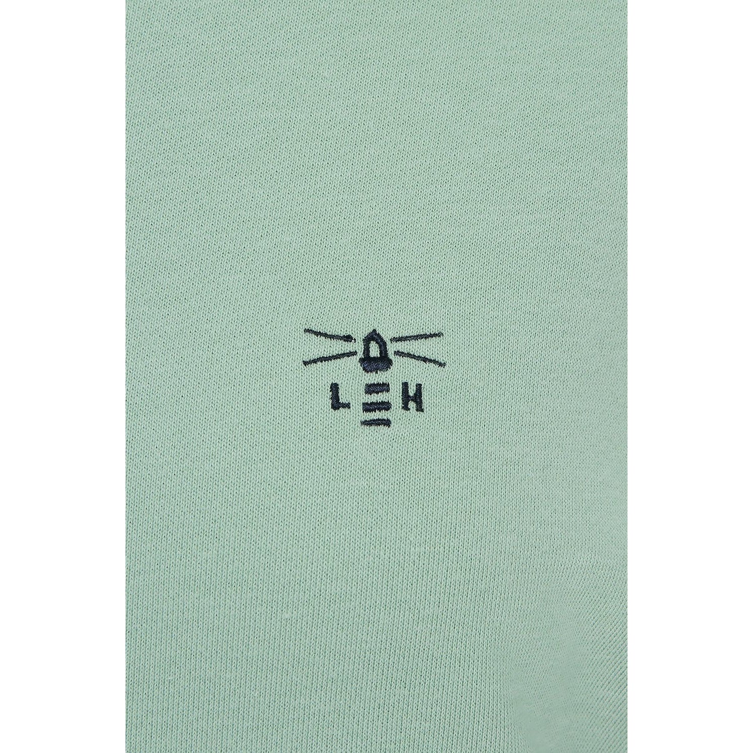 Close-up view of the embroidered logo of a Lighthouse women's Seaside crew neck sweatshirt in Pastel Green.
