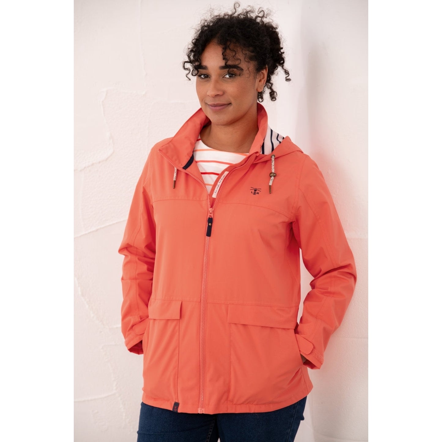 Front view of a woman wearing a Beachcomber II waterproof jacket in Coral.