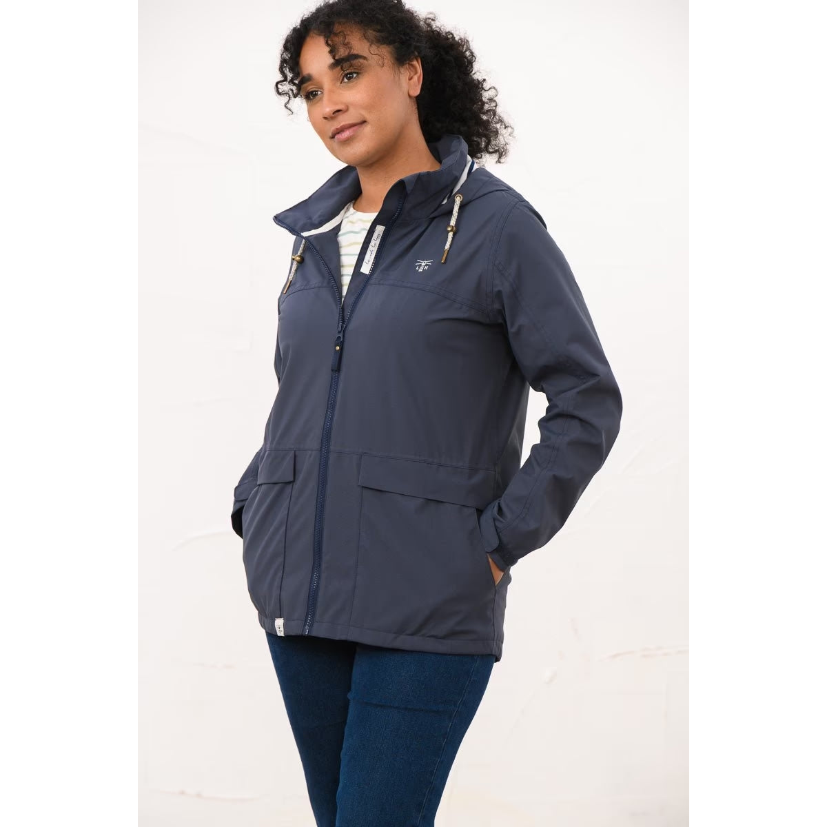 Side view of a woman wearing a Lighthouse navy Beachcomber II waterproof jacket with hands in the front pockets.