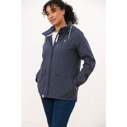 Side view of a woman wearing a Lighthouse navy Beachcomber II waterproof jacket with hands in the front pockets.