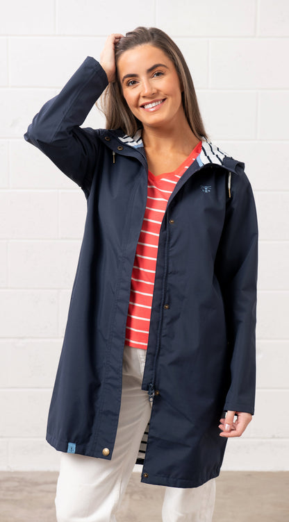 Front view of the Lighthouse womens navy waterproof jacket worn by smiling woman with hood and striped inner lining