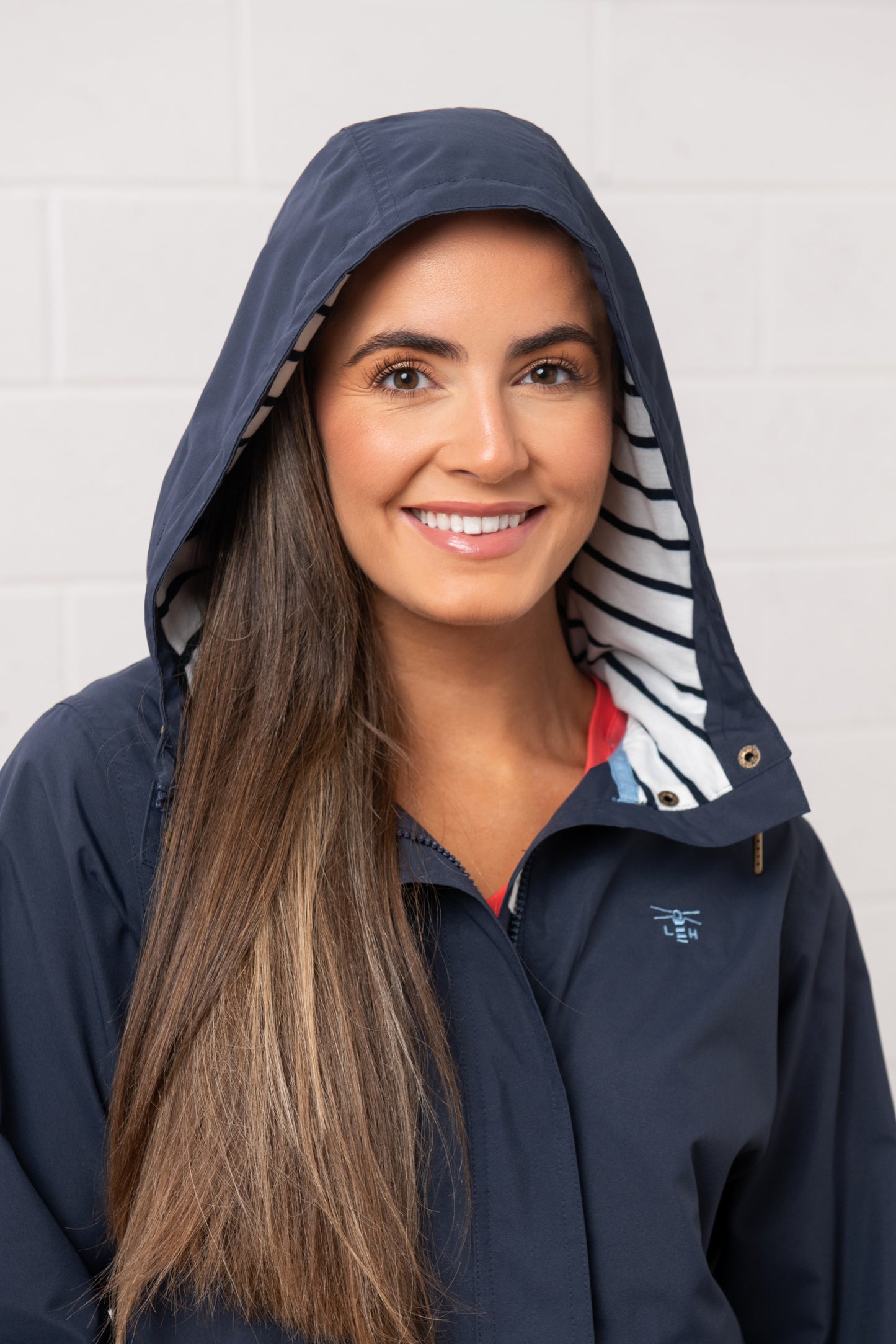 Lighthouse womens navy waterproof jacket with striped hood lining worn by smiling woman